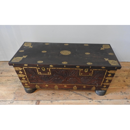 106 - A CARVED HARDWOOD EASTERN STORAGE TRUNK, with decorative brass mounts and banding throughout, the fr... 