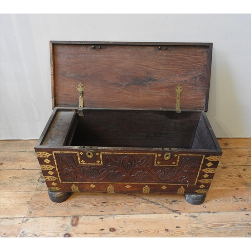 106 - A CARVED HARDWOOD EASTERN STORAGE TRUNK, with decorative brass mounts and banding throughout, the fr... 