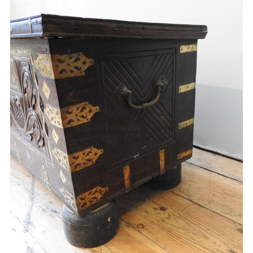 106 - A CARVED HARDWOOD EASTERN STORAGE TRUNK, with decorative brass mounts and banding throughout, the fr... 