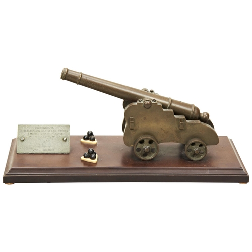 123 - A BRASS MODEL OF AN 18TH CENTURY SHIP'S CANNON mounted on a Bakelite base with two stands of cannon ... 