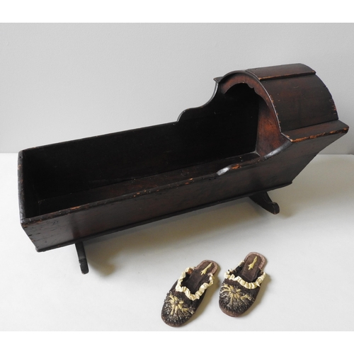 310 - A 19TH CENTURY PINE DOLL'S CRADLE AND A PAIR OF 19TH CENTURY LEATHER SOLED SLIPPERS, the cradle meas... 