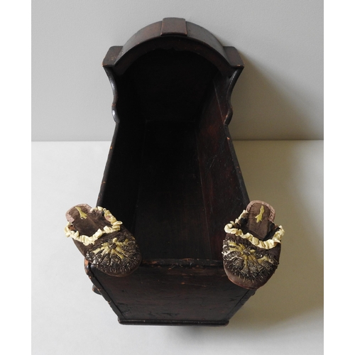 310 - A 19TH CENTURY PINE DOLL'S CRADLE AND A PAIR OF 19TH CENTURY LEATHER SOLED SLIPPERS, the cradle meas... 