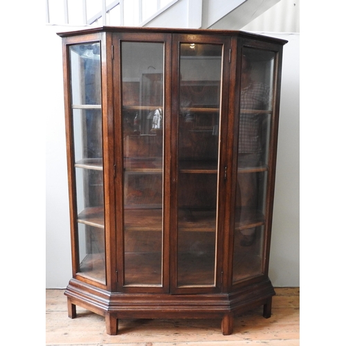 30 - A CONTEMPORARY HARDWOOD DISPLAY CABINET, with canted sides, the two glazed doors open to reveal thre... 