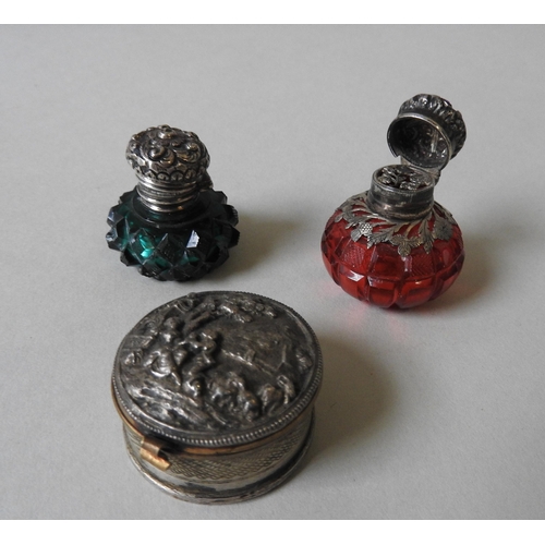 341 - TWO VICTORIAN SILVER MOUNTED SCENT BOTTLES AND A WHITE METAL PILL BOX, the ruby and emerald glass sc... 