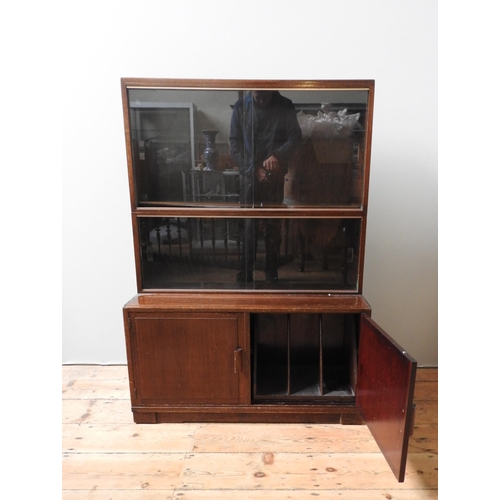 63 - A MODULAR MID CENTURY MAHOGANY BOOKCASE, with two top sections with sliding glass doors, sat atop a ... 