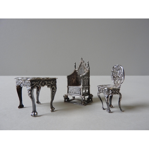 348 - THREE PIECES OF MINIATURE SILVER DOLL'S FURNITURE, comprising of an ornate repousse decorated table ... 