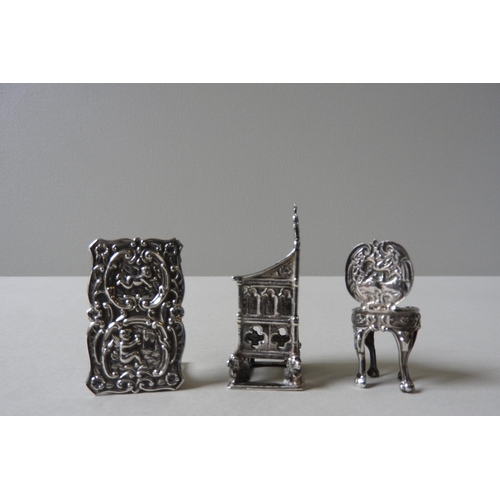 348 - THREE PIECES OF MINIATURE SILVER DOLL'S FURNITURE, comprising of an ornate repousse decorated table ... 