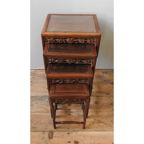 76 - A NEST OF FOUR CHINESE HARDWOOD TABLES, with ornate carved frieze panels, max height 71 x 42 x 34 cm