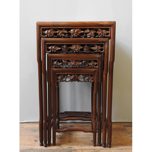 76 - A NEST OF FOUR CHINESE HARDWOOD TABLES, with ornate carved frieze panels, max height 71 x 42 x 34 cm