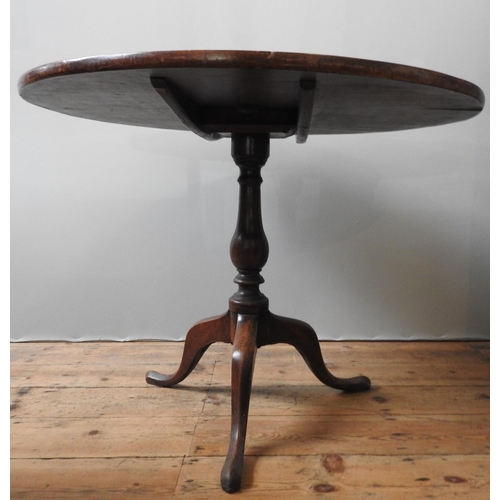 77 - A GEORGE III MAHOGANY TILT TOP TRIPOD TABLE, the circular single piece top sat atop a turned baluste... 