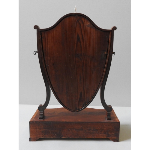 250 - A GEORGE III MAHOGANY TABLE MIRROR, of shield form, on a serpentine base with three frieze drawers, ... 