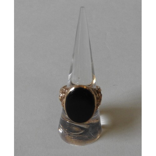 376 - A 9CT GOLD SIGNET RING, set with an oval black onyx, the shoulders engraved with rococo-style acanth... 