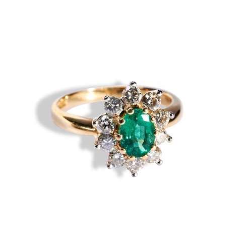 112 - AN EMERALD AND DIAMOND CLUSTER RING the central oval cut emerald set above ten round cut diamonds on... 