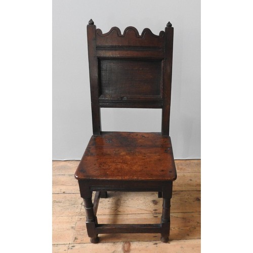 38 - AN 18TH CENTURY OAK HALL CHAIR, of simplistic form, with a carved shaped top rail above a plain pane... 