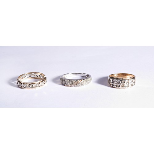 224 - THREE WHITE STONE DRESS RINGSAn eternity set gold and white metal dress ring, millegrain set with to... 