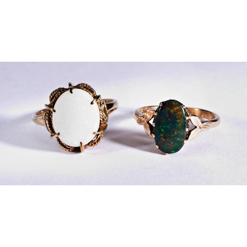 231 - TWO GOLD OPAL DRESS RINGSA bolder opal doublet claw set ring with decorative floral shoulders to a s... 