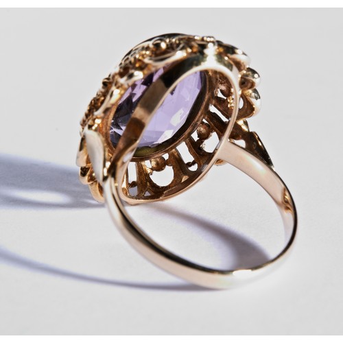 244 - A PURPLE STONE DRESS RINGthe bezel set, mixed cut oval stone, surrounded by rope and wire decoration... 