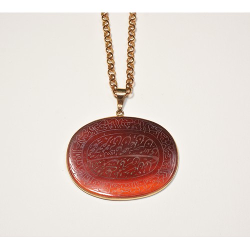 245 - AN ENGRAVED CARNELIAN PENDANT NECKLACEAn engraved oval carnelian bezel set with articulated bale and... 