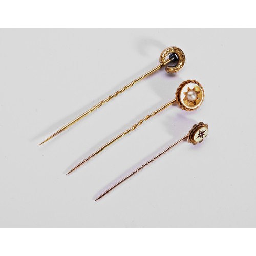 274 - THREE LATE 19TH CENTURY STICK PINSA yellow metal stick pin in the form of a horse shoe Unmarked Weig... 