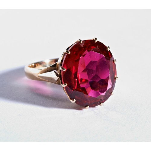 290 - A SYNTHETIC RUBY RINGthe oval mixed cut, claw set, synthetic ruby to a pierced gallery between split... 