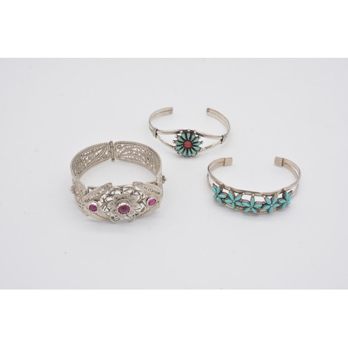 300 - A COLLECTION OF CUFF BRACELETSIncluding a silver cuff set central flower design, set with red a blue... 