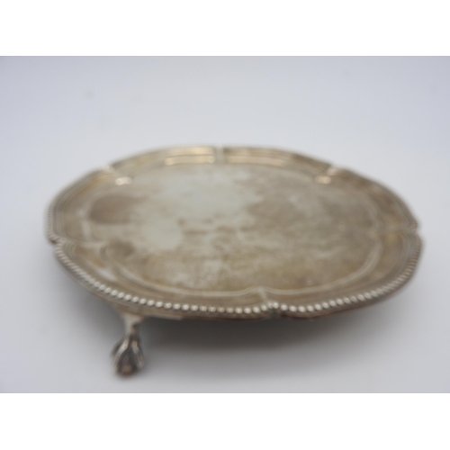 525 - A SMALL SILVER SALVER, with a beaded scroll work edge, raised on three claw and ball feet, bears the... 