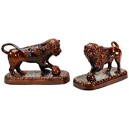 255 - A PAIR OF STAFFORDSHIRE TREACLE-GLAZE LIONS19TH CENTURYthe confronting beasts standing with one paw ... 