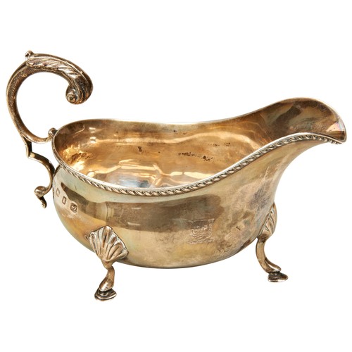 478 - A SILVER SAUCE BOAT, with scroll foliate handle, gadrooned edge, raised on three hoof feet, bears th... 