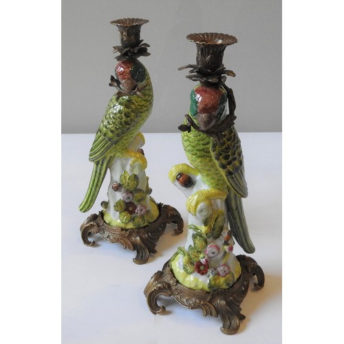 375 - A PAIR OF CERAMIC CANDLESTICKS IN THE FORM OF GREEN PARROTS, perched atop a naturalistic tree stump ... 