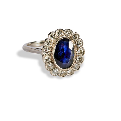 89 - A DIAMOND AND SAPPHIRE OVAL CLUSTER RINGconsisting of a central oval Sapphire in rub over setting wi... 