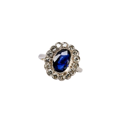 89 - A DIAMOND AND SAPPHIRE OVAL CLUSTER RINGconsisting of a central oval Sapphire in rub over setting wi... 