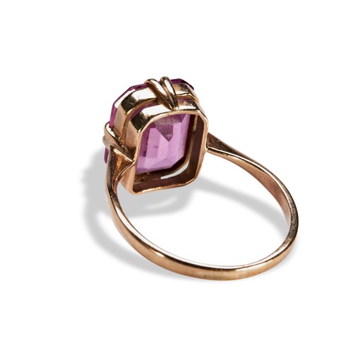 109 - A PINK SYNTHETIC SAPPHIRE RINGthe emerald-cut, cut cornered, pink synthetic sapphire being set betwe... 