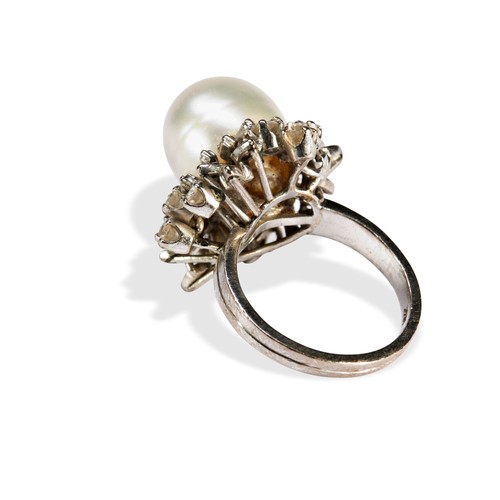 115 - A PEARL AND DIAMOND RINGset with a large central oval pearl, surrounded by a mixture of round brilli... 