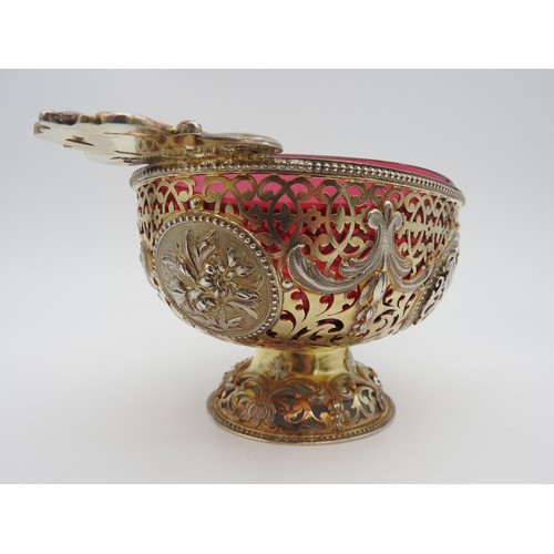 291 - AN UNUSUAL SILVER GILT OVAL BOWL, with cranberry glass liner, pierced scroll work sides emblazoned w... 