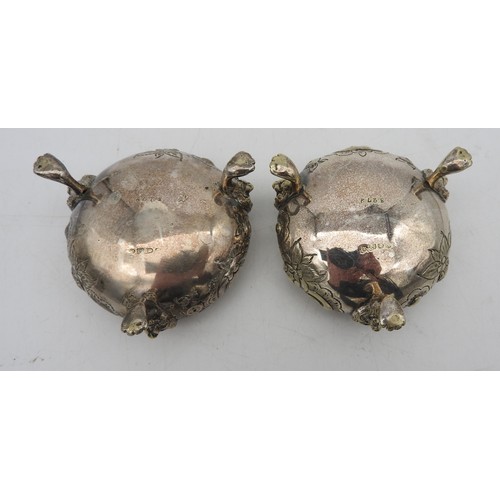 341 - A PAIR OF SILVER PLATED SALTS, gadrooned rims with scroll foliate repousse decoration, raised on thr... 