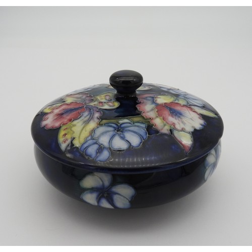 372 - A MOORCROFT CIRCULAR BOX AND COVER, CIRCA 1950, vibrant orchid decoration on a deep blue ground, imp... 