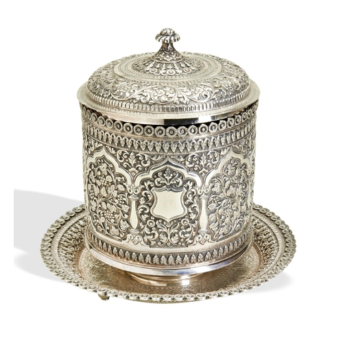 144 - A KUTCH SILVER BISCUIT BOX C.1890. The jar has an integral base and lift off lid. The reserves aroun... 