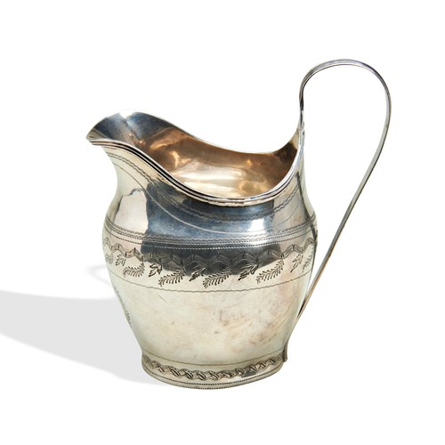 257 - A GEORGE III SILVER CREAM JUG, helmet form with bright cut banded decoration and monogram cartouche,... 