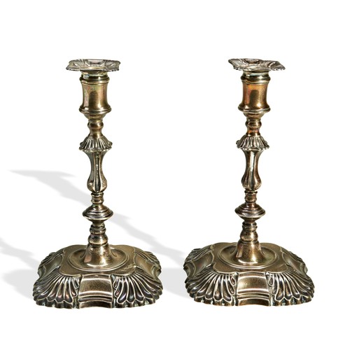 240 - A PAIR OF WEIGHTED SILVER CANDLESTICKS,  of small proportion, in a George II style with fluted knop ... 