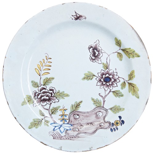 129 - AN 18TH CENTURY DELFTWARE POLYCHROME PLATE, depicting peonies, ferns and a butterfly, with an underg... 