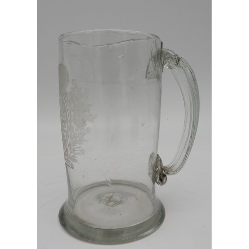 118 - A GEORGE III GLASS TANKARD, CIRCA 1820, with etched heraldic crest cartouche flanked by foliate bord... 