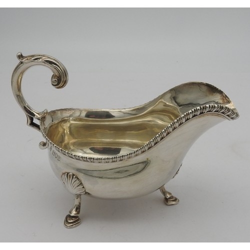 279 - A LATE VICTORIAN SILVER SAUCE BOAT, helmet form with gadrooned edge and scrolling handle, raised on ... 