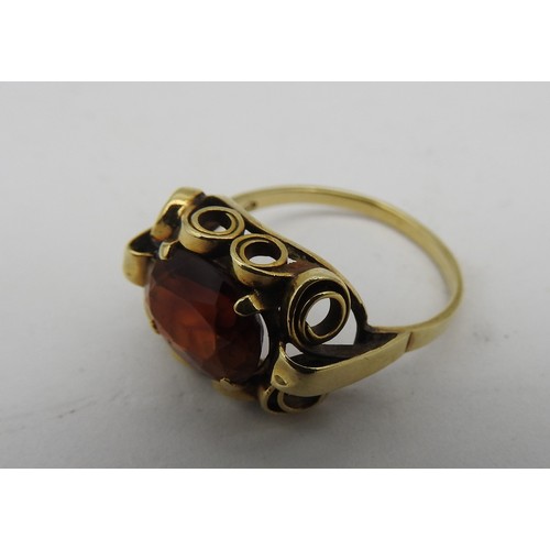 334 - A HESSONITE 14CT GOLD GARNET SET RING, the oval garnet in an unusual scroll work setting, stamped 58... 