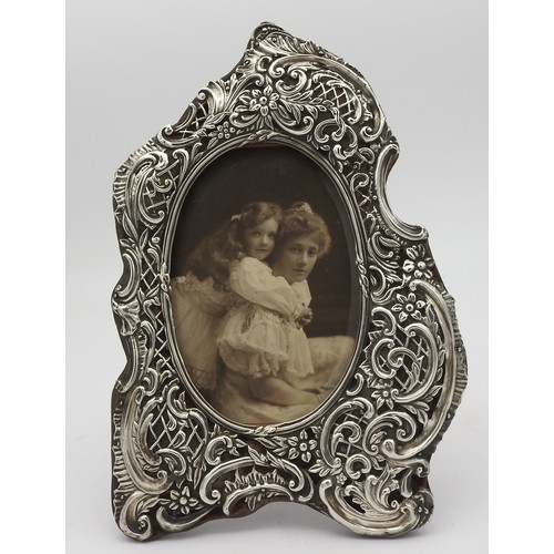 236 - AN ORNATE SILVER PICTURE FRAME, 20TH CENTURY, elegant cartouche shape with scroll foliate and floral... 