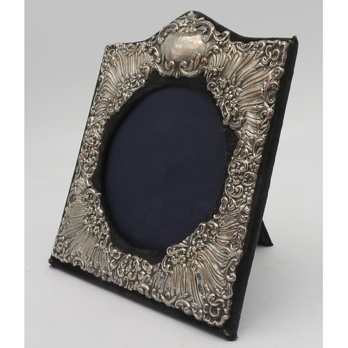 235 - AN ORNATE SILVER PHOTO FRAME, square form with arched cartouche top, with floral repousse decoration... 