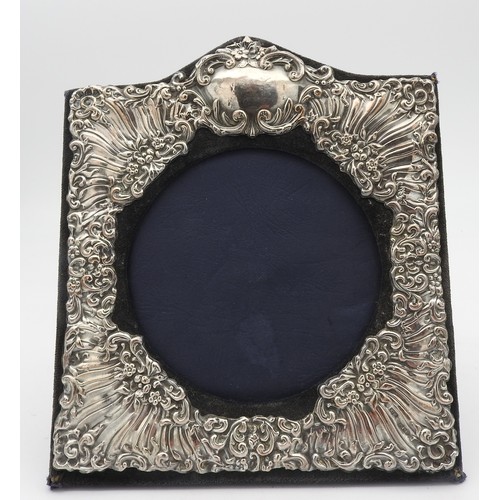 235 - AN ORNATE SILVER PHOTO FRAME, square form with arched cartouche top, with floral repousse decoration... 