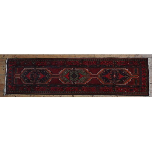 73 - A HAND KNOTTED PERSIAN HAMADAN RUNNER, 20TH CENTURY, three central medallions within a deep border, ... 