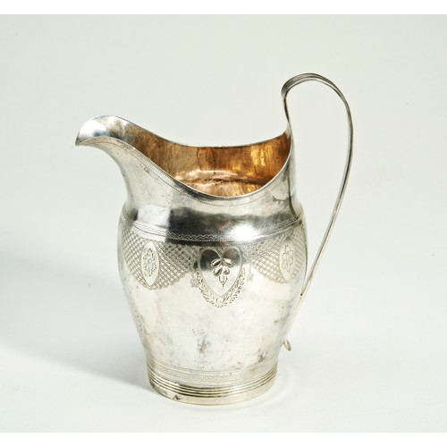 285 - A GEORGE III SILVER CREAM JUG, helmet form, with bright cut reserves decorated with rosettes and han... 