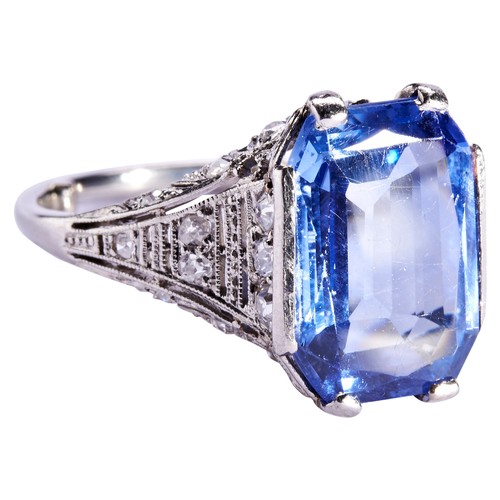 303 - A SAPPHIRE AND DIAMOND RING, CIRCA 1920the emerald-cut, cut cornered sapphire four claw, set above a... 