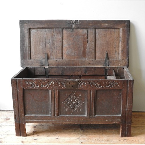 66 - A GEORGE II OAK THREE PANEL COFFER, CIRCA 1740, simplistic country form, with a foliate carved friez... 